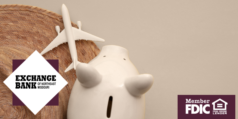 White piggy bank next to white airplane on sand colored background