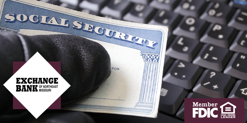 Black glove holding social security card over keyboard