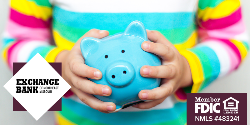 Child's hands holding a blue piggy bank 